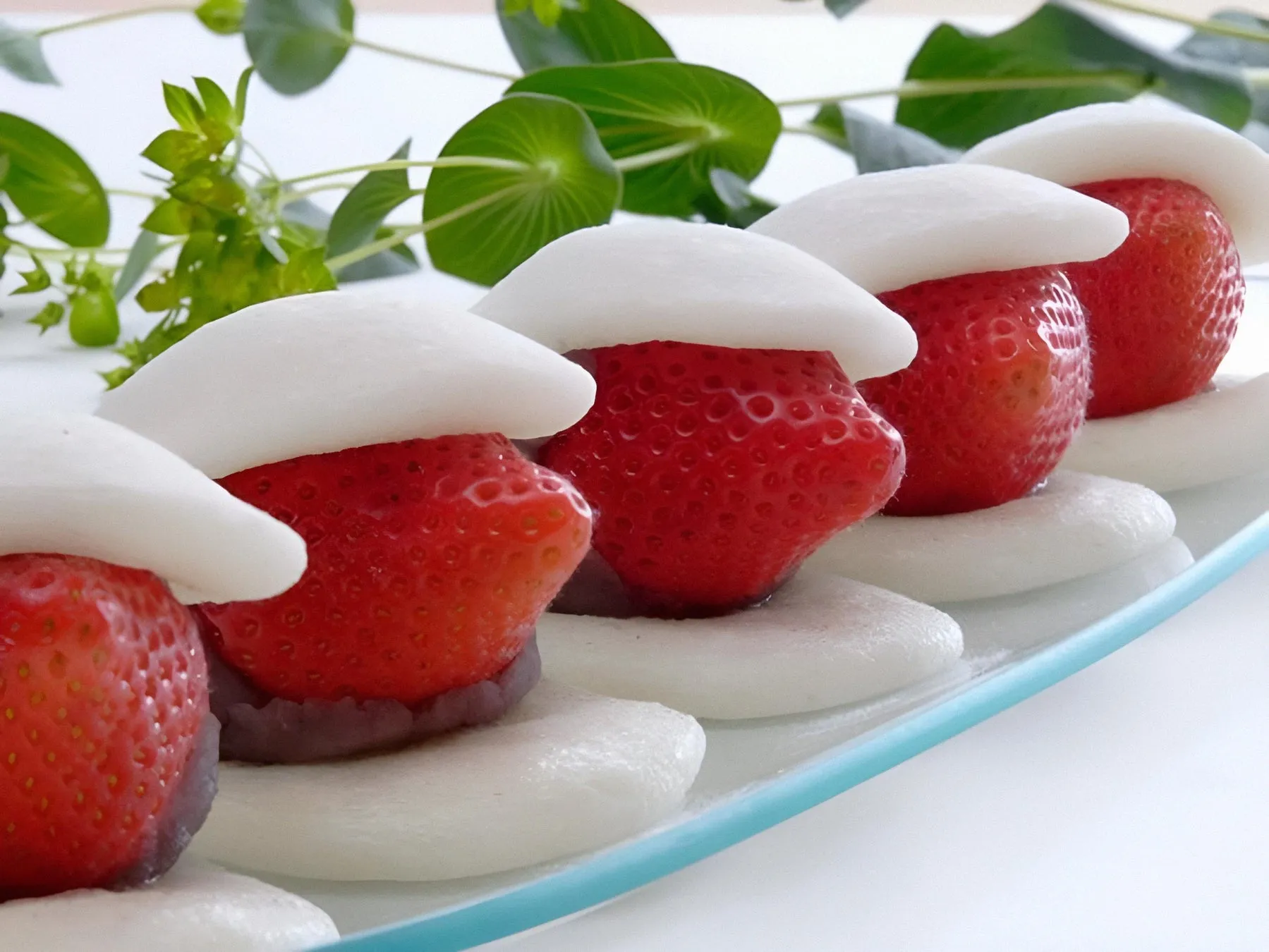 いちご大福が並んだ写真です。白い餅、赤いいちご、緑の葉が写っています。