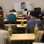 教室で講義を受けている学生たちの写真。
