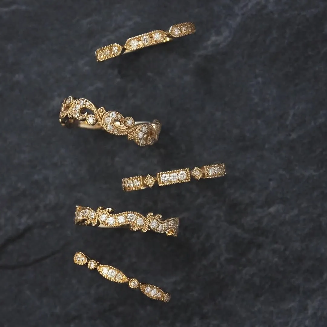 黒い背景に、様々なデザインのゴールドの指輪がいくつか並べられている写真