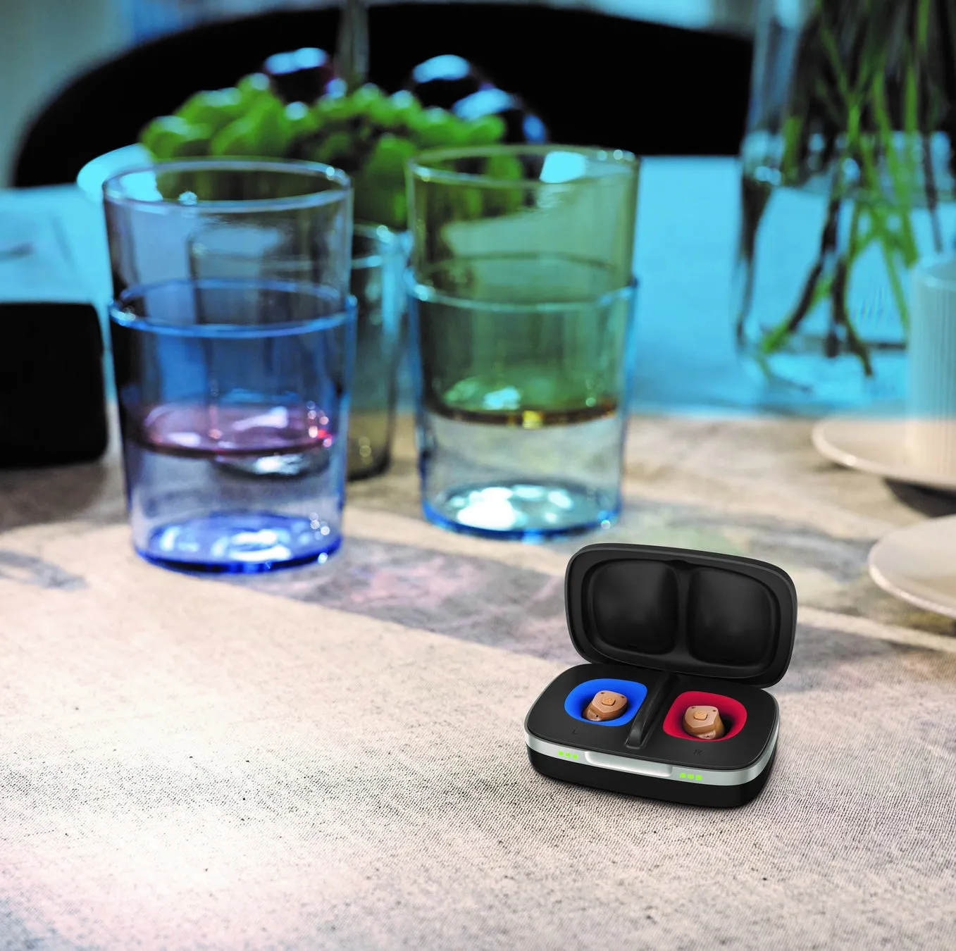 補聴器と充電器のクローズアップ写真。ケースには、青と赤のコンパートメントにそれぞれ補聴器が入っている。