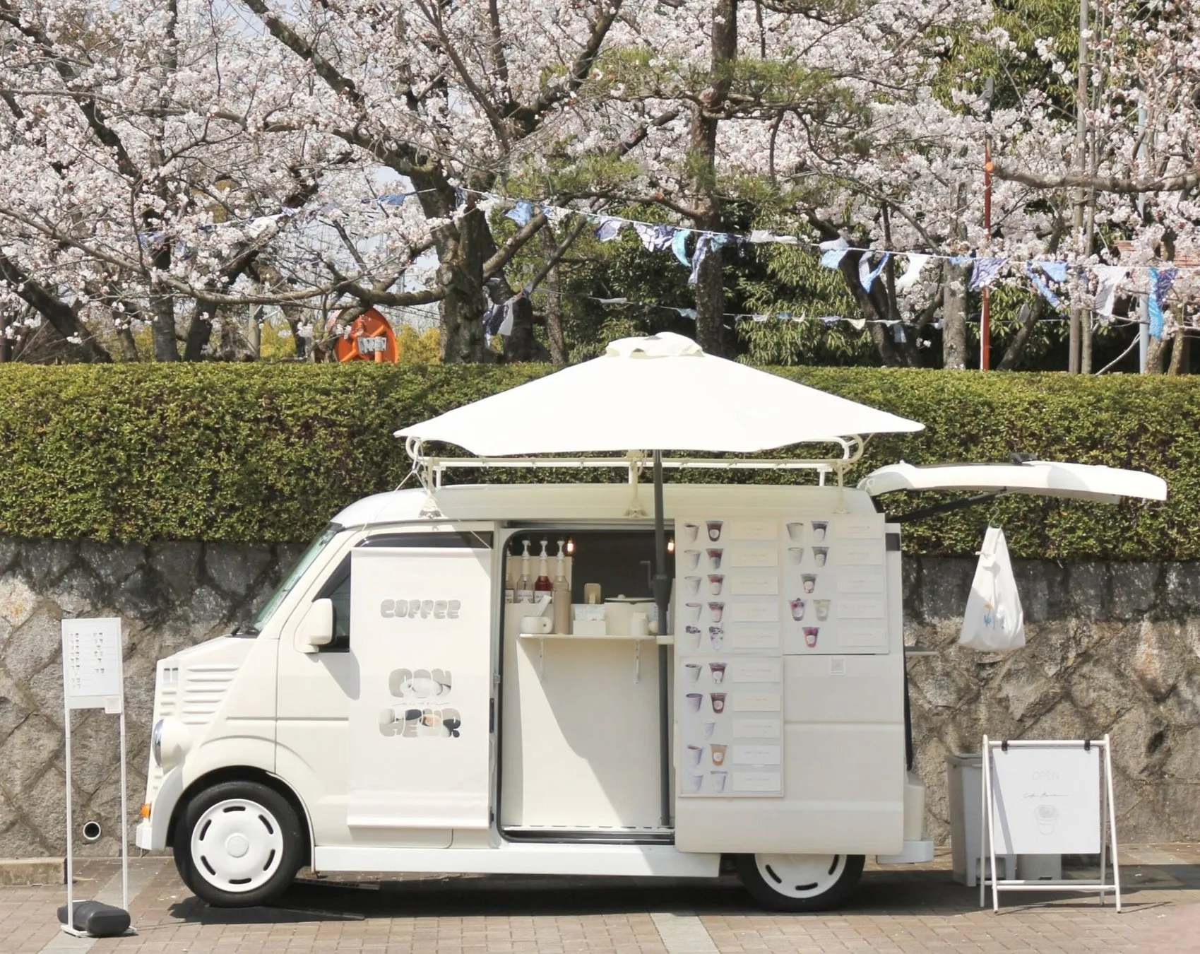 桜の木の下にある白いコーヒーショップの車