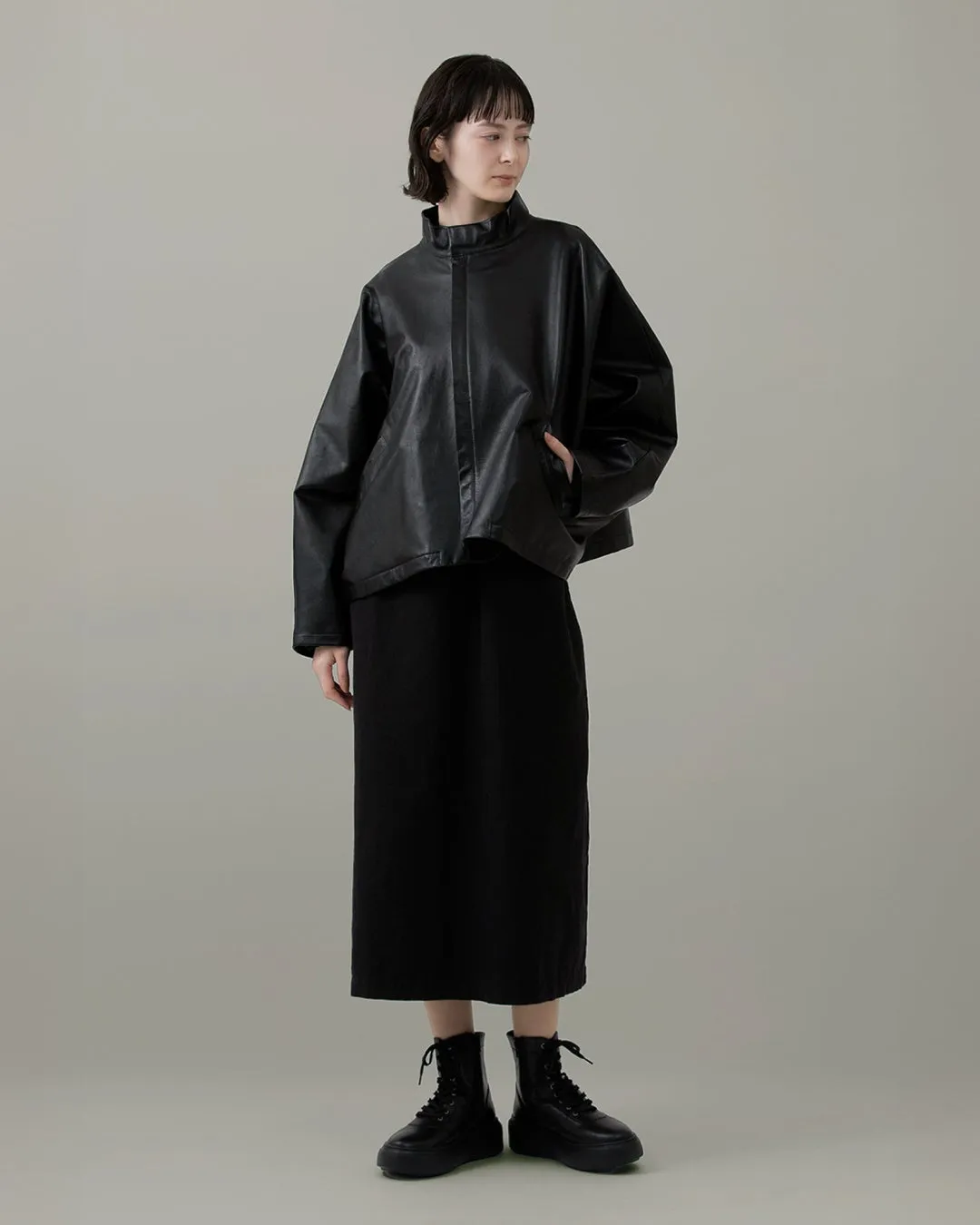 黒いジャケットとスカートを着てブーツを履いた女性