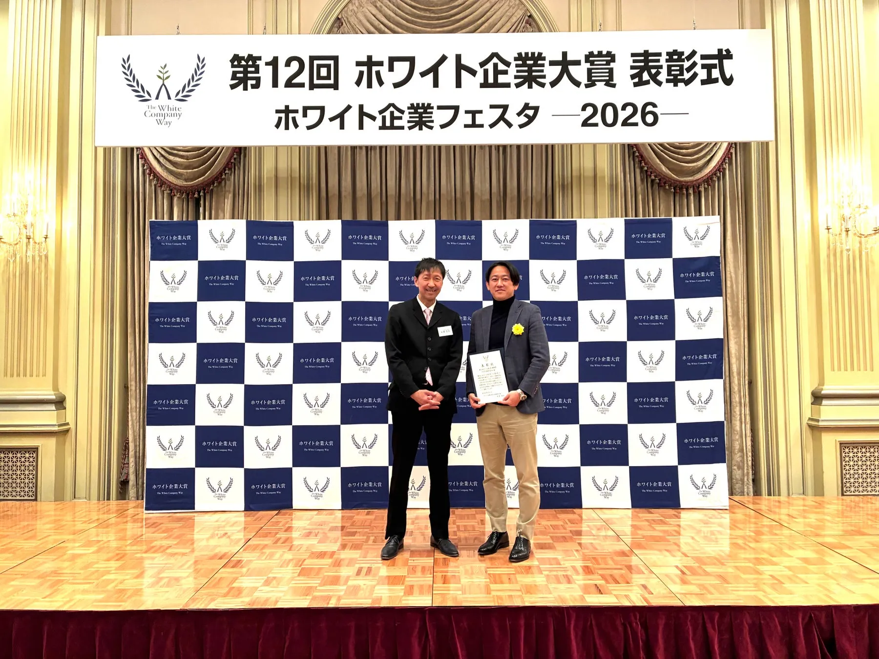 表彰式で賞状を持つ2人の男性