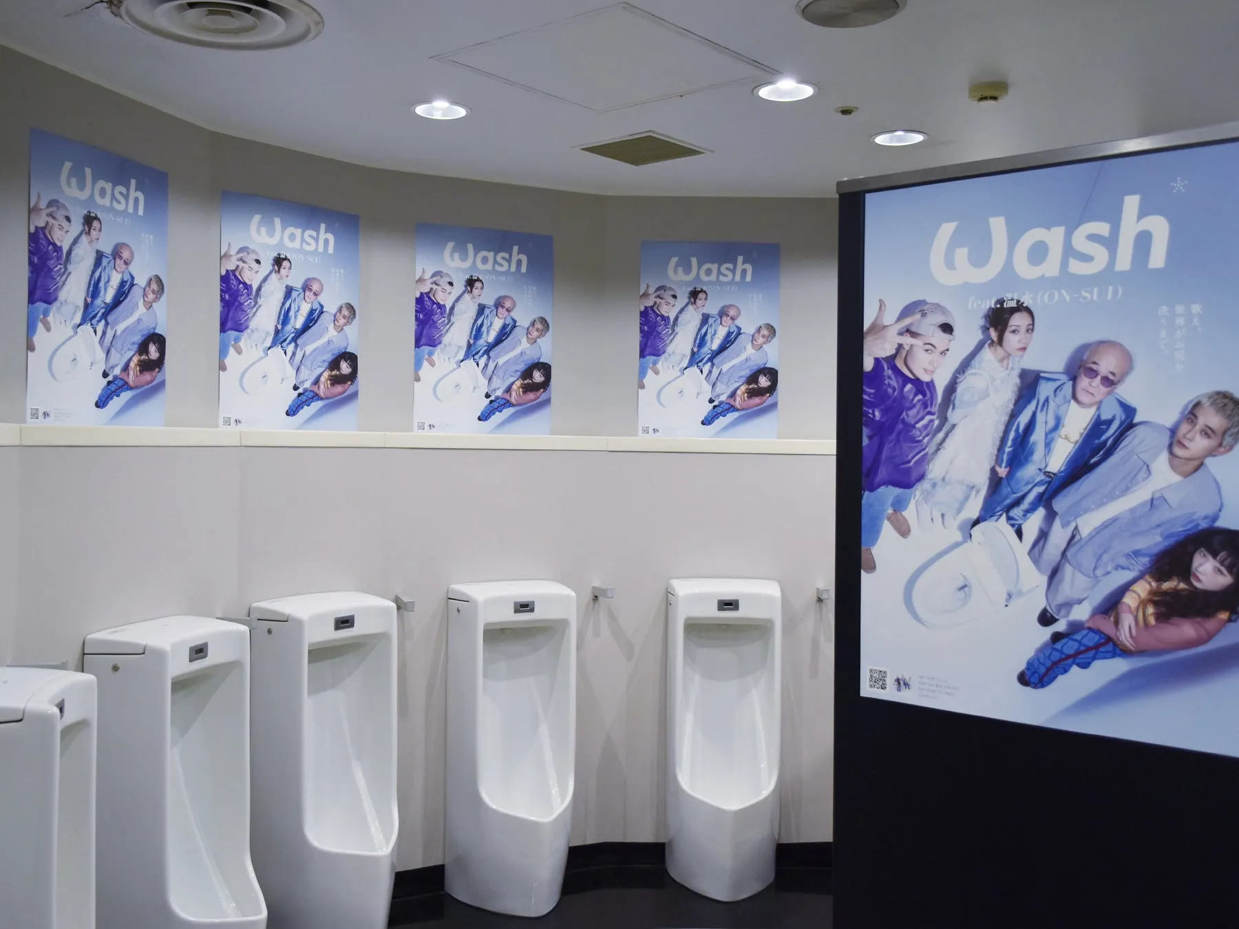 男性用トイレの壁に貼られたWash feat.温水(ON-SUI)のプロモーションポスター。