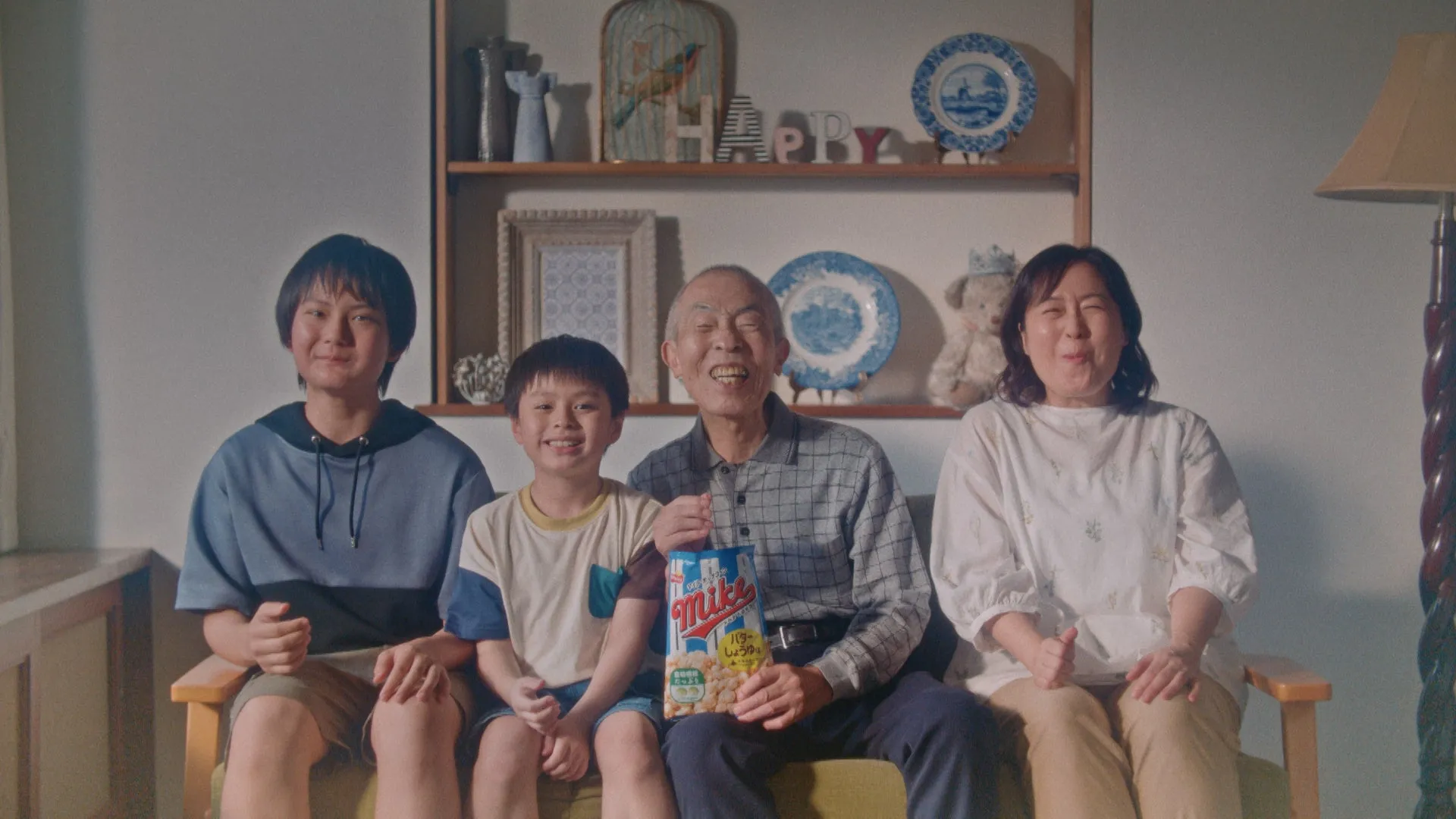 4人家族がソファーに座って、お菓子を食べている写真。