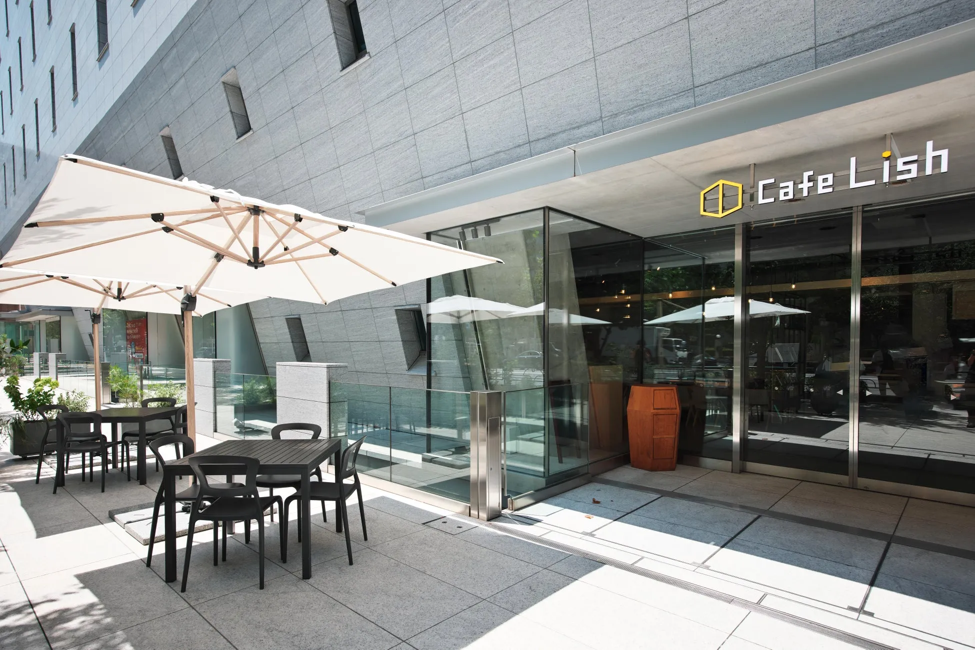 カフェLishの屋外席の様子。白いパラソルとテーブル、椅子が配置され、建物の外観と調和している。