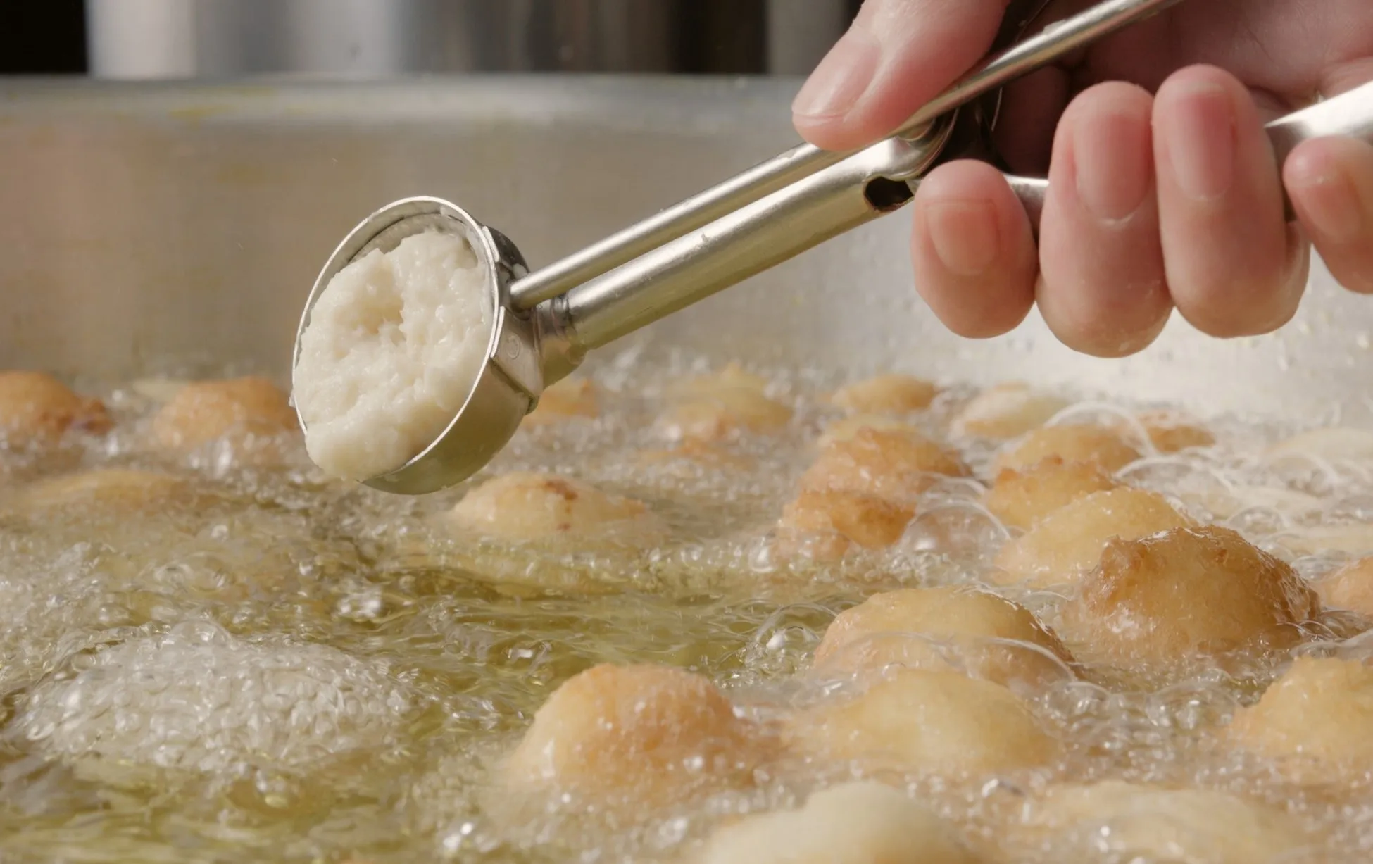 揚げ物を作っている様子。丸い生地を油の中に落とし、調理している様子が写っています。