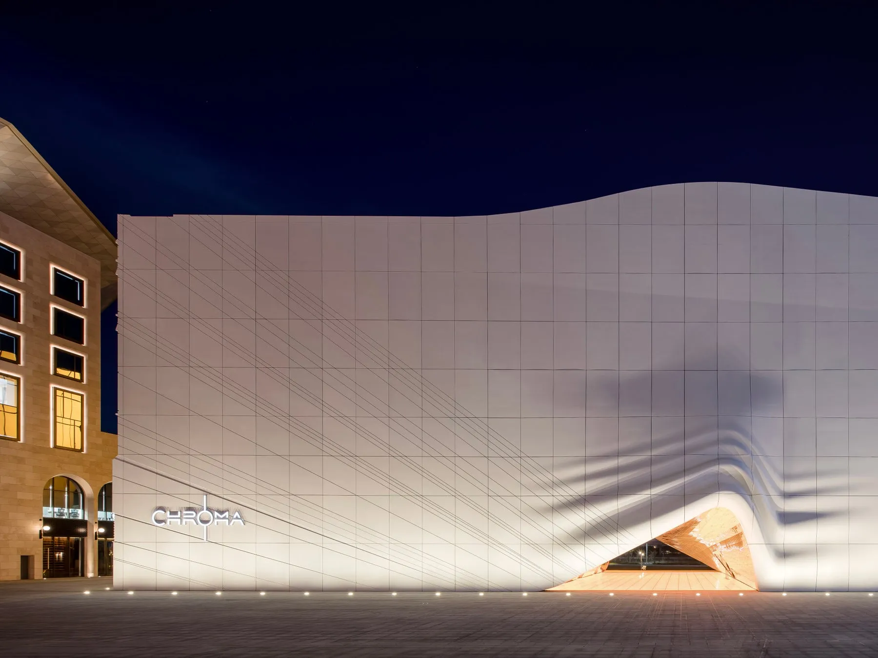 夜の建物。白い壁にCHROMAの文字が光っている