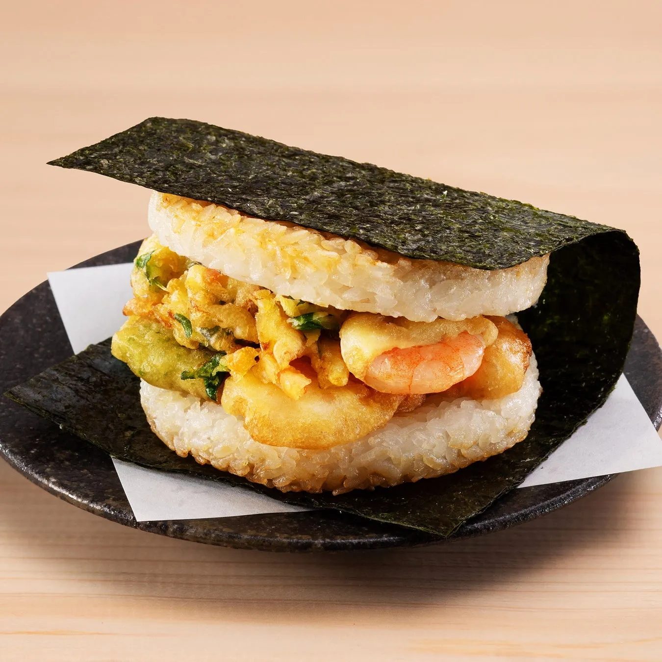 海苔で挟まれたおにぎりサンド。中にはエビや野菜の天ぷらが入っている。