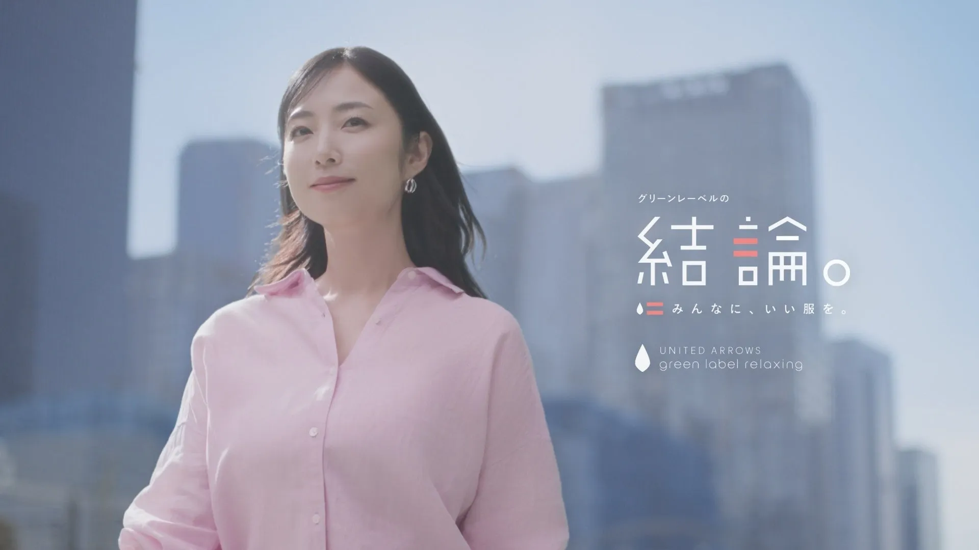 ピンクのシャツを着た女性が、街を背景に微笑んでいる広告画像。"グリーンレーベルの結論。みんなに、いい服を。"というテキストと、UNITED ARROWS green label relaxingのロゴが表示されている。