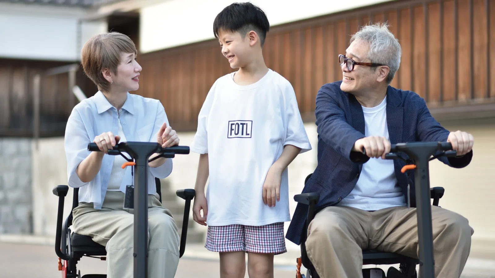 電動車椅子に乗った3人家族。子供と両親が楽しそうにしている様子。