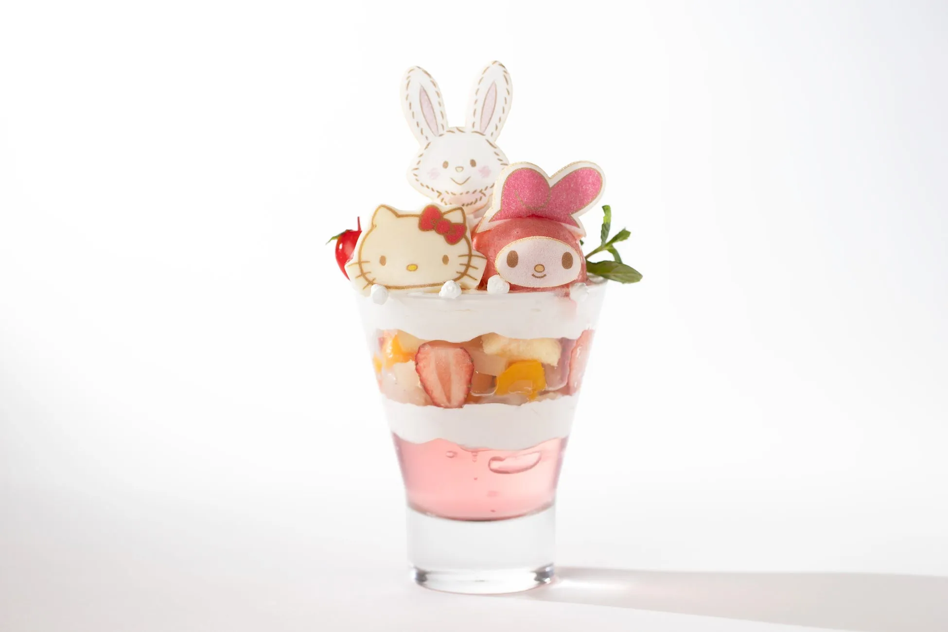 ハローキティとマイメロディ、ウサギのクッキーがトッピングされたパフェ。ピンク色のゼリー、フルーツ、クリームが層になっている。