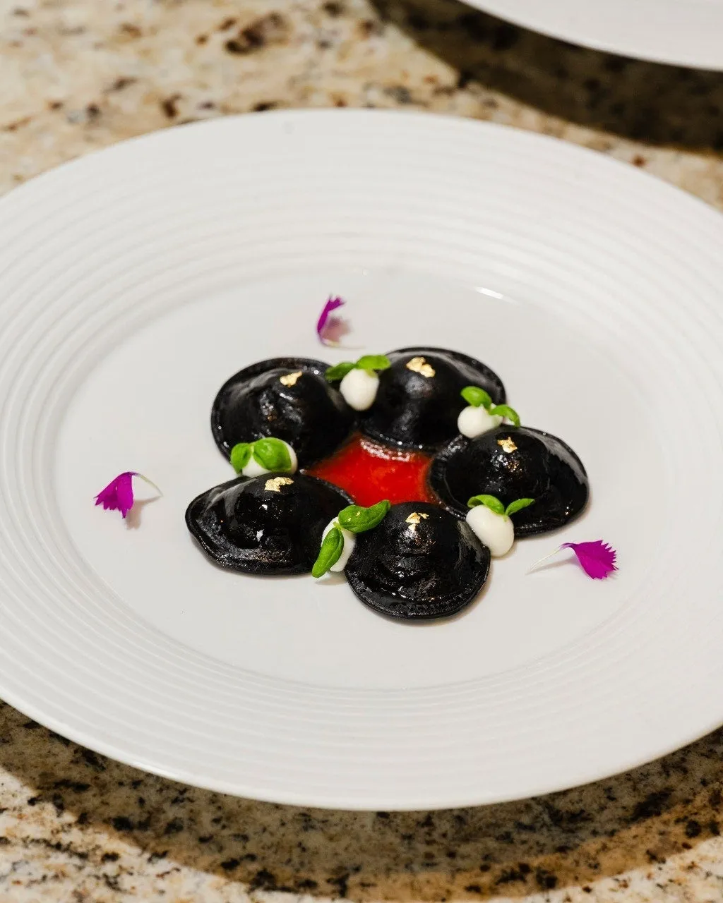 黒いラビオリが白い皿に盛り付けられた料理
