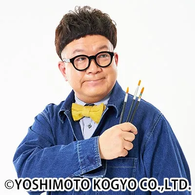 眼鏡をかけた男性が、蝶ネクタイとブラシを持ってカメラ目線で微笑んでいる写真です。