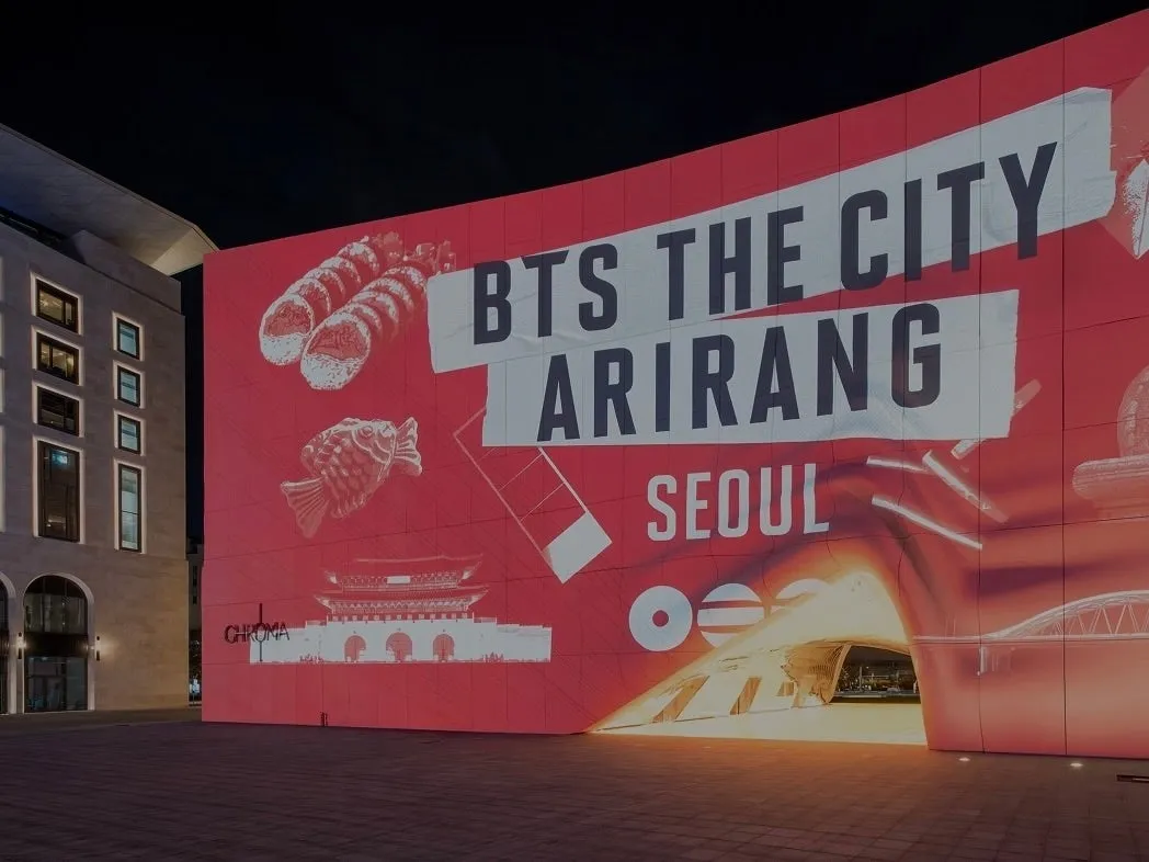 夜の街並みに、BTSのイベント「BTS THE CITY ARIRANG SEOUL」の広告が表示されている様子